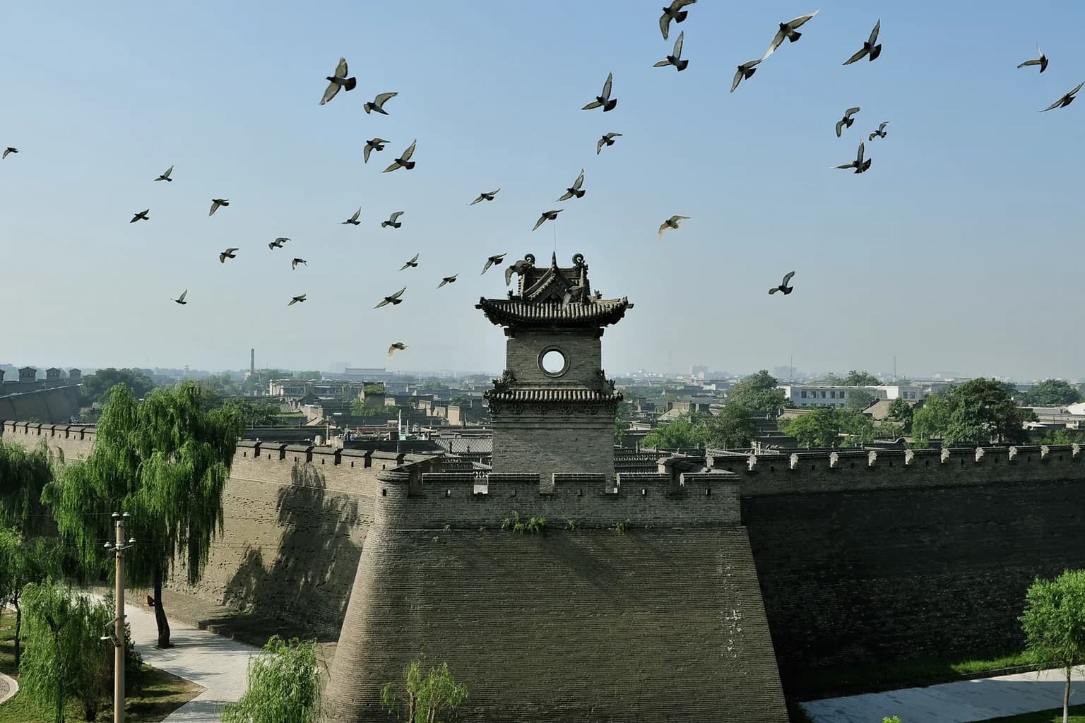 Pingyao Ancient City wall and gate tower beneath a flock of birds